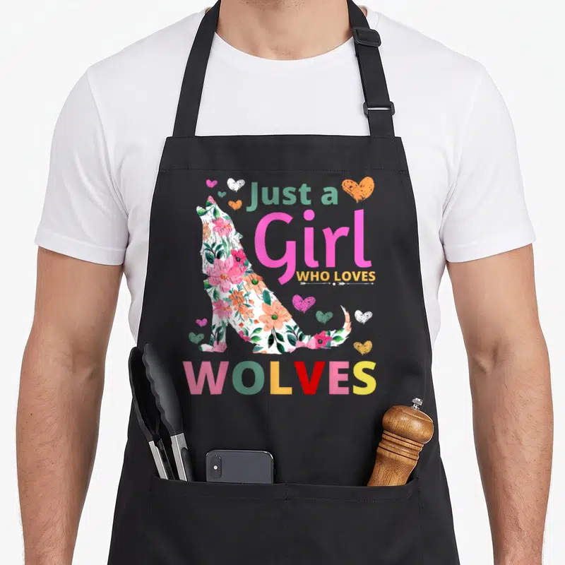 Wolve floral apron - Floral wolf silhouette with hearts and text Just a Girl WHO LOVES WOLVES in pink yellow and green — shown on a black cotton canvas apron against a white background