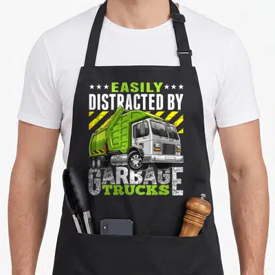 Easily distracted truck apron - Cartoon lime green garbage truck with yellow stripes and text EASILY DISTRACTED — shown on a black cotton canvas apron against a white background