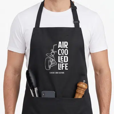 Beach car apron - White motorcycle line drawing next to stacked AIR COOLED LIFE text — shown on a black cotton canvas apron against a white background