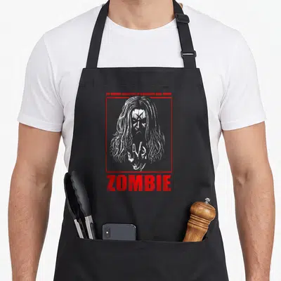 Rob tribute apron - White zombie head and hand inside red frame with distressed red text above and below — shown on a black cotton canvas apron against a white background