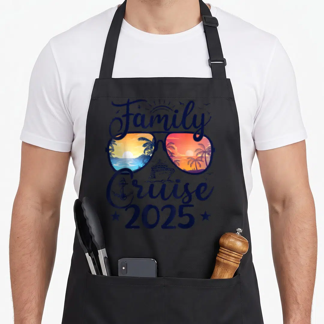 Cruise summer family aprons - Sunglasses with tropical sunset reflections, cruise ship, anchor, and 2025 text in navy — shown on a black cotton canvas apron against a white background