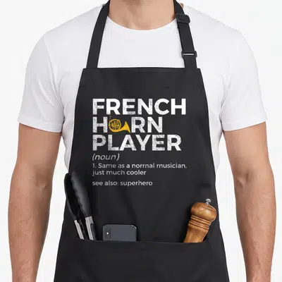 Player french apron - Distressed white text reading French Horn Player with yellow horn graphic inside the O — shown on a black cotton canvas apron against a white background
