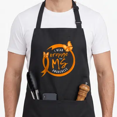 Sclerosis manuscript apron - Orange ribbon circle with two butterflies and text I Wear Orange for MS Awareness — shown on a black cotton canvas apron against a white background