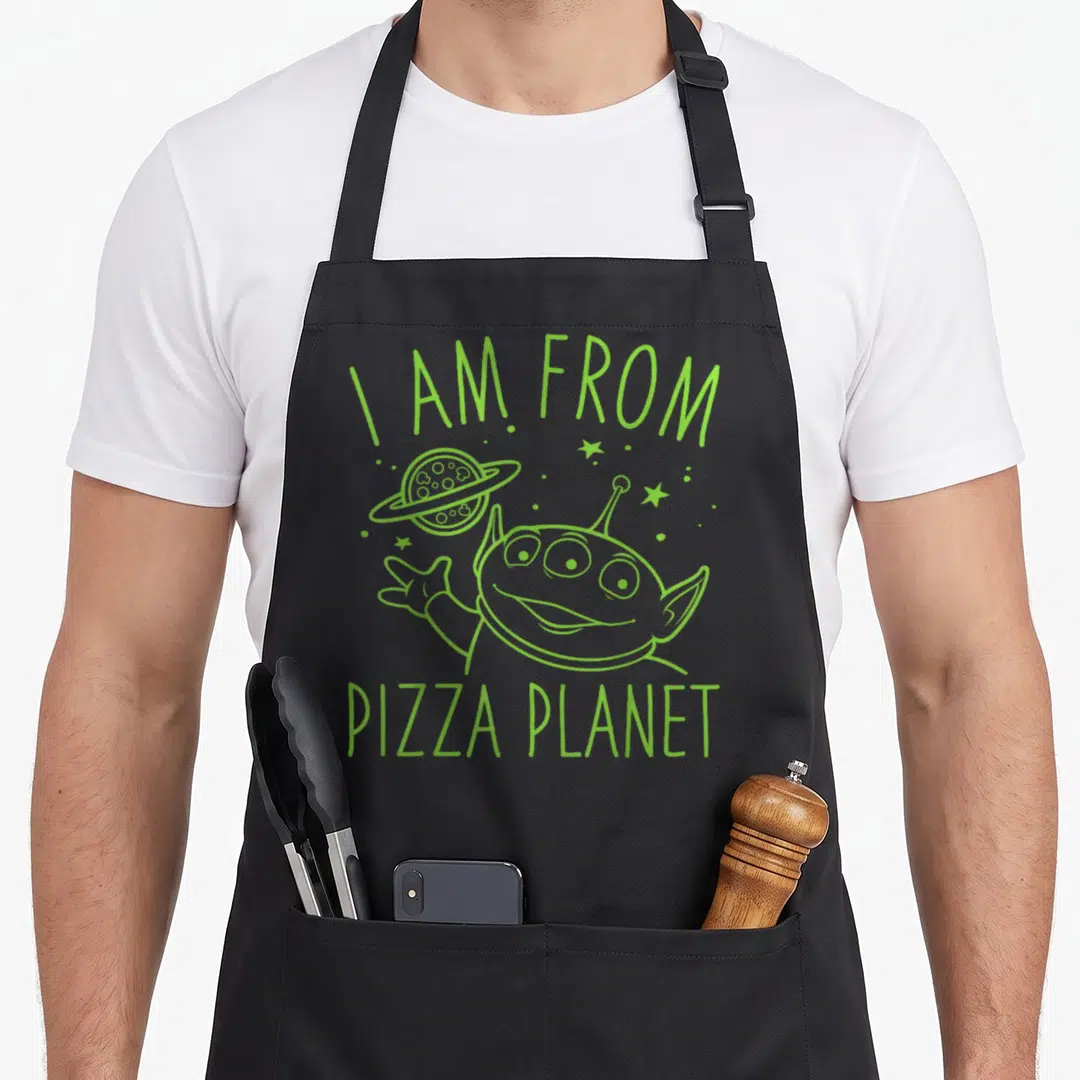 Neon pizza planet apron - Lime green line art alien waving next to ringed planet with text I AM FROM PIZZA PLANET — shown on a black cotton canvas apron against a white background