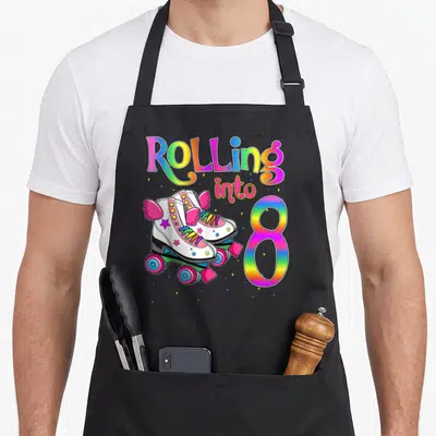 Roller turning apron - Rolling into 8 text with two winged roller skates and scattered stars in pink yellow blue green — shown on a black cotton canvas apron against a white background