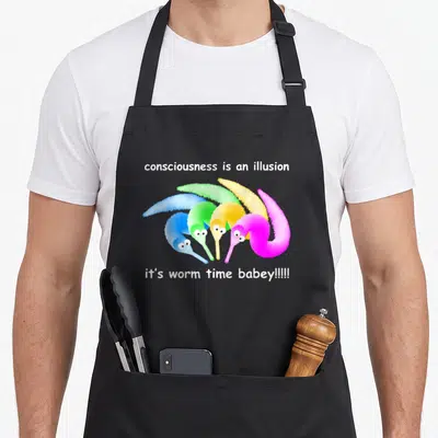 Death magic apron - Five colorful cartoon worms between white text reading consciousness is an illusion and worm time — shown on a black cotton canvas apron against a white background