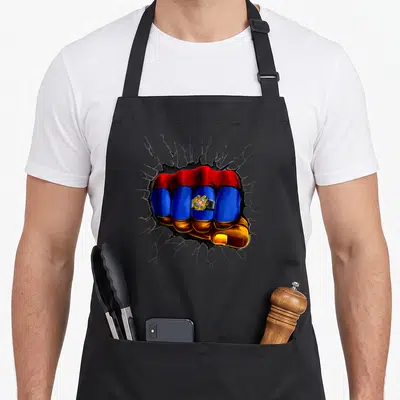 Armenia flag armenian apron - Fist filled with red blue yellow and black punching through cracked surface with emblem — shown on a black cotton canvas apron against a white background