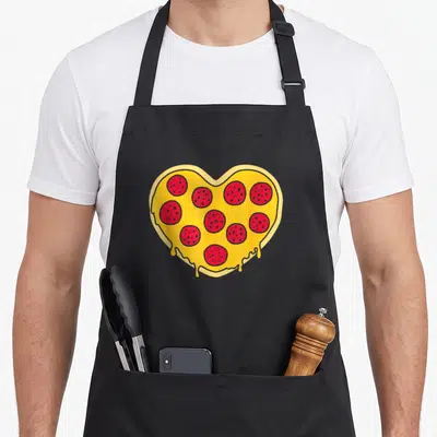 Vintage food pizza apron - Cartoon heart-shaped pizza with red pepperoni and yellow cheese dripping — shown on a black cotton canvas apron against a white background