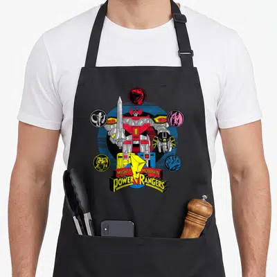 Megazord rangers apron - Red and silver robot surrounded by five colored dinosaur head icons and logo text — shown on a black cotton canvas apron against a white background