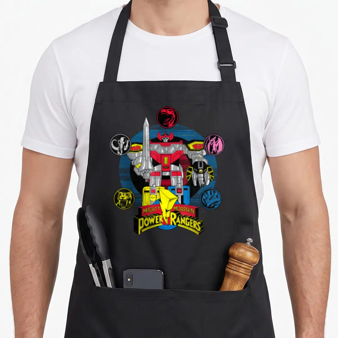 Megazord rangers apron - Red and silver robot surrounded by five colored dinosaur head icons and logo text — shown on a black cotton canvas apron against a white background