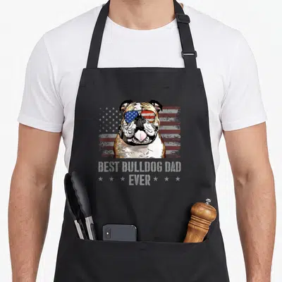 Bulldog dog american flag apron - Bulldog wearing flag sunglasses with Best Bulldog Dad Ever text on distressed — shown on a black cotton canvas apron against a white background