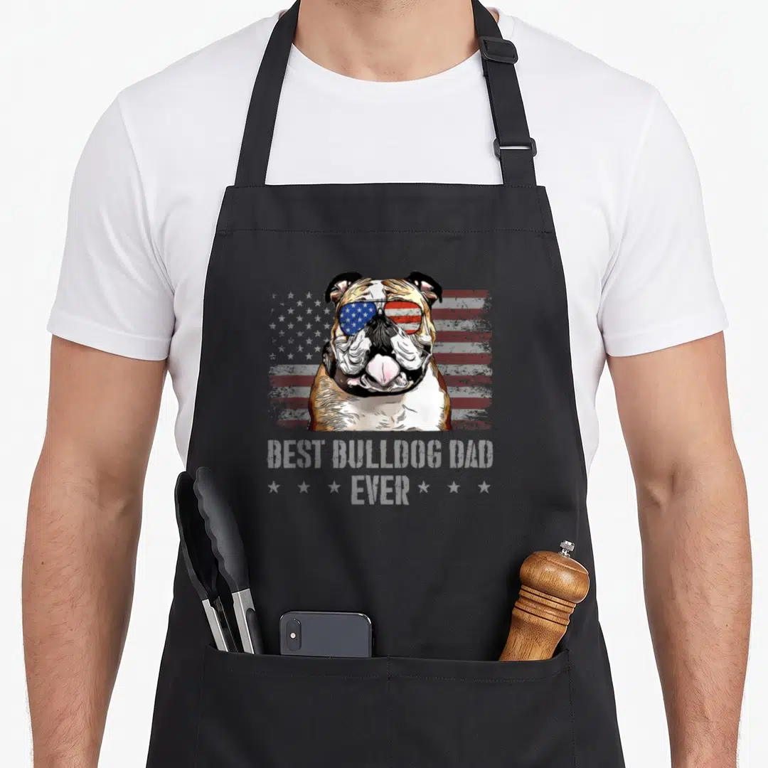 Bulldog dog american flag apron - Bulldog wearing flag sunglasses with Best Bulldog Dad Ever text on distressed — shown on a black cotton canvas apron against a white background
