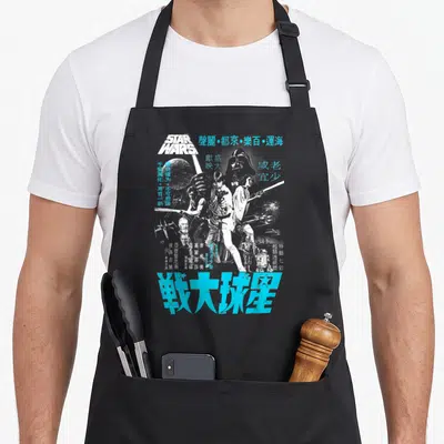 Kanji hope apron - Star Wars character collage with distressed Chinese text in blue and white — shown on a black cotton canvas apron against a white background