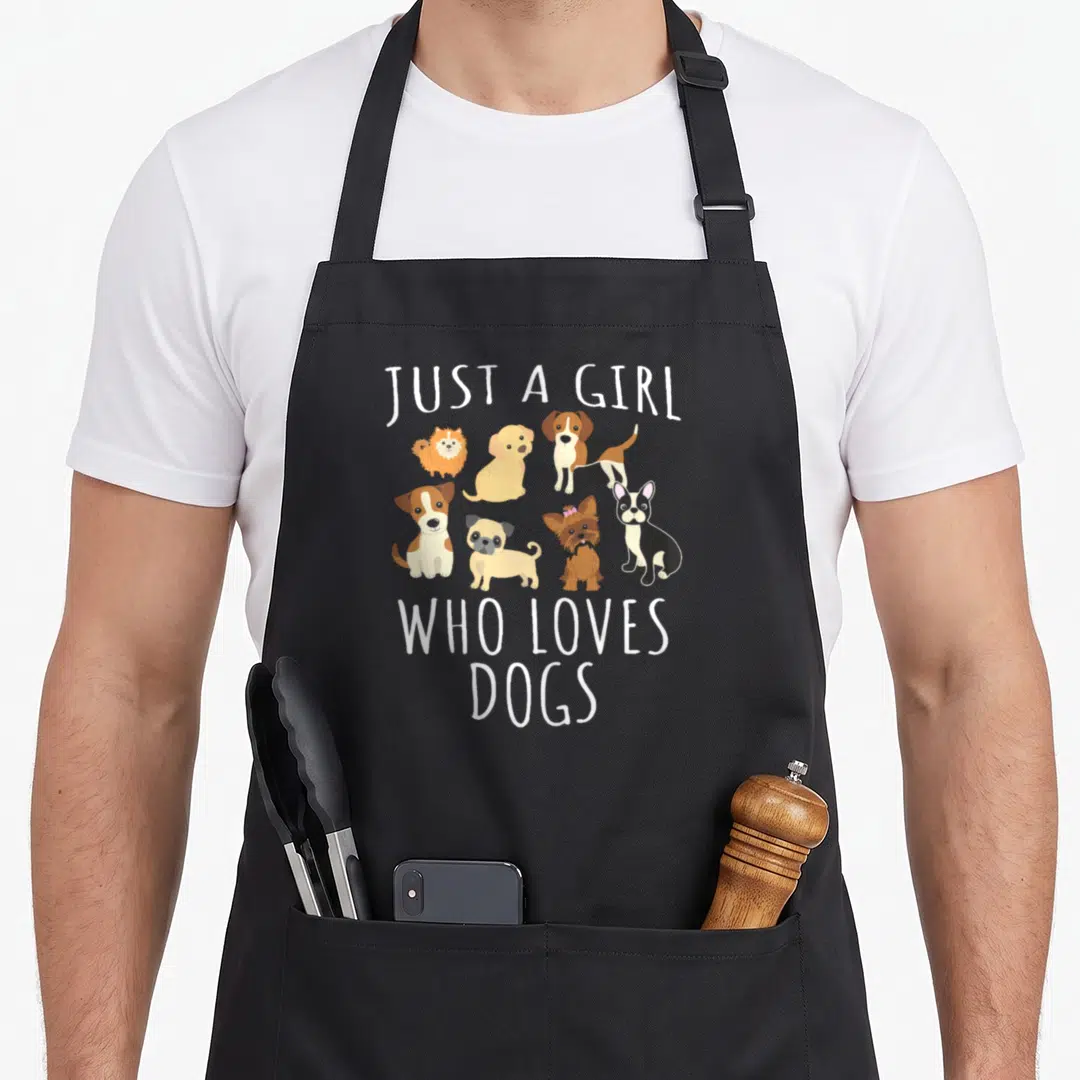 Puppy dog apron - Six cartoon dogs in white brown tan and black with text JUST A GIRL WHO LOVES DOGS — shown on a black cotton canvas apron against a white background