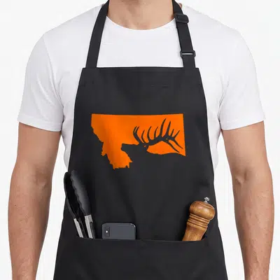 Montana elk apron - Orange Montana state map silhouette containing a grey elk antler graphic — shown on a black cotton canvas apron against a white background