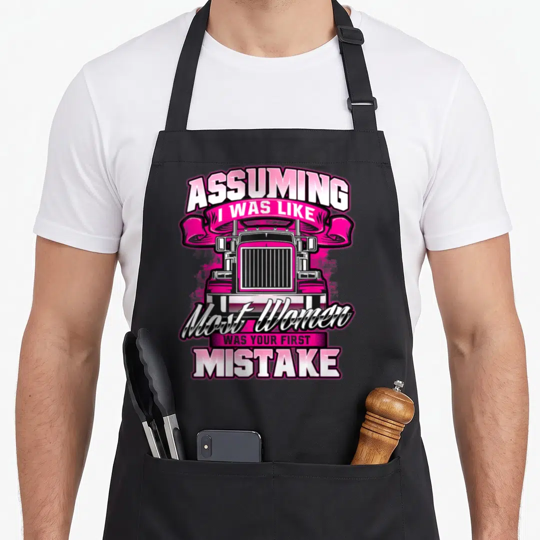 Mistake semi truck apron - Pink ribbon and cartoon truck with sarcastic text about being a first mistake — shown on a black cotton canvas apron against a white background