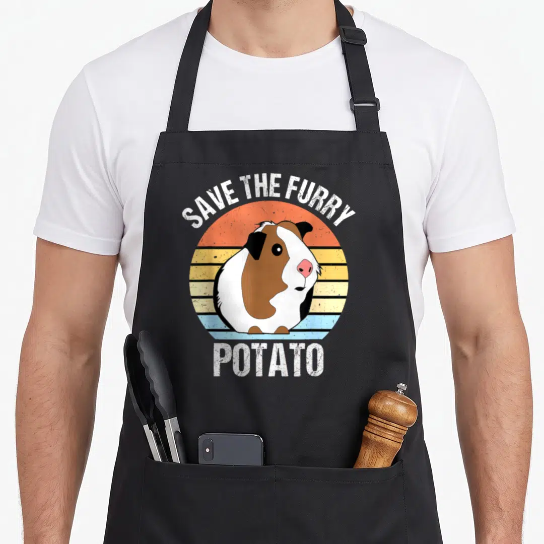 Furry potato apron - Guinea pig in striped circle with text SAVE THE FURRY POTATO — shown on a black cotton canvas apron against a white background