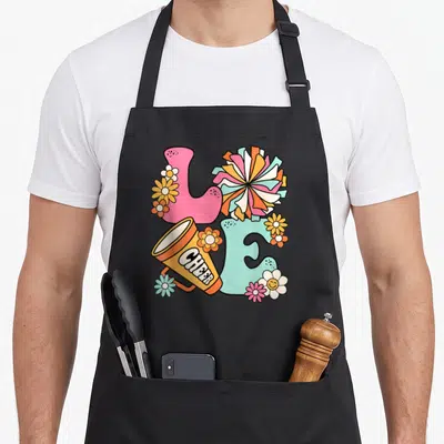 Cute cheer cheerleader cheerleading apron - Cartoon LOVE letters with megaphone saying CHEER, pink and blue blocks — shown on a black cotton canvas apron against a white background