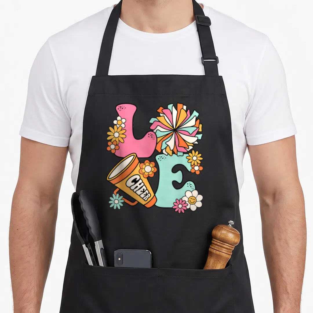Cute cheer cheerleader cheerleading apron - Cartoon LOVE letters with megaphone saying CHEER, pink and blue blocks — shown on a black cotton canvas apron against a white background