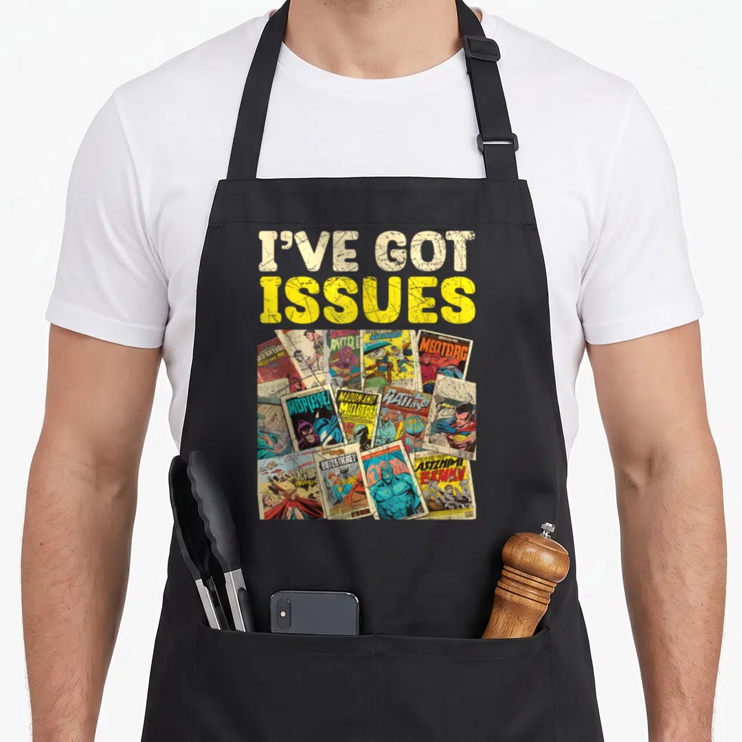 Collector comics apron - I've Got Issues text above overlapping comic books in yellow, beige, blue, and red — shown on a black cotton canvas apron against a white background