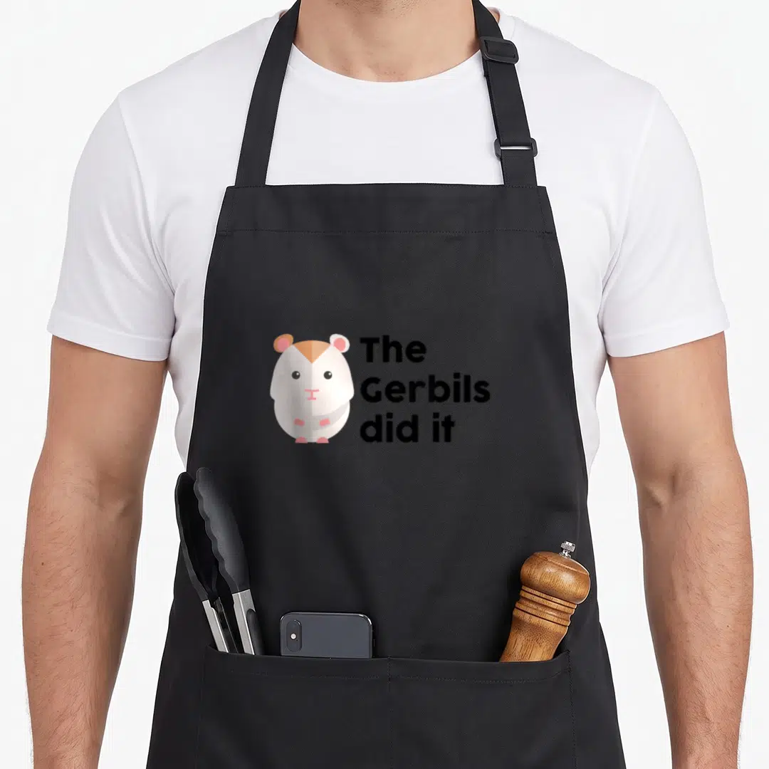 Funny best gerbil apron - Stylized gerbil in white brown pink next to black text reading The Gerbils did it — shown on a black cotton canvas apron against a white background