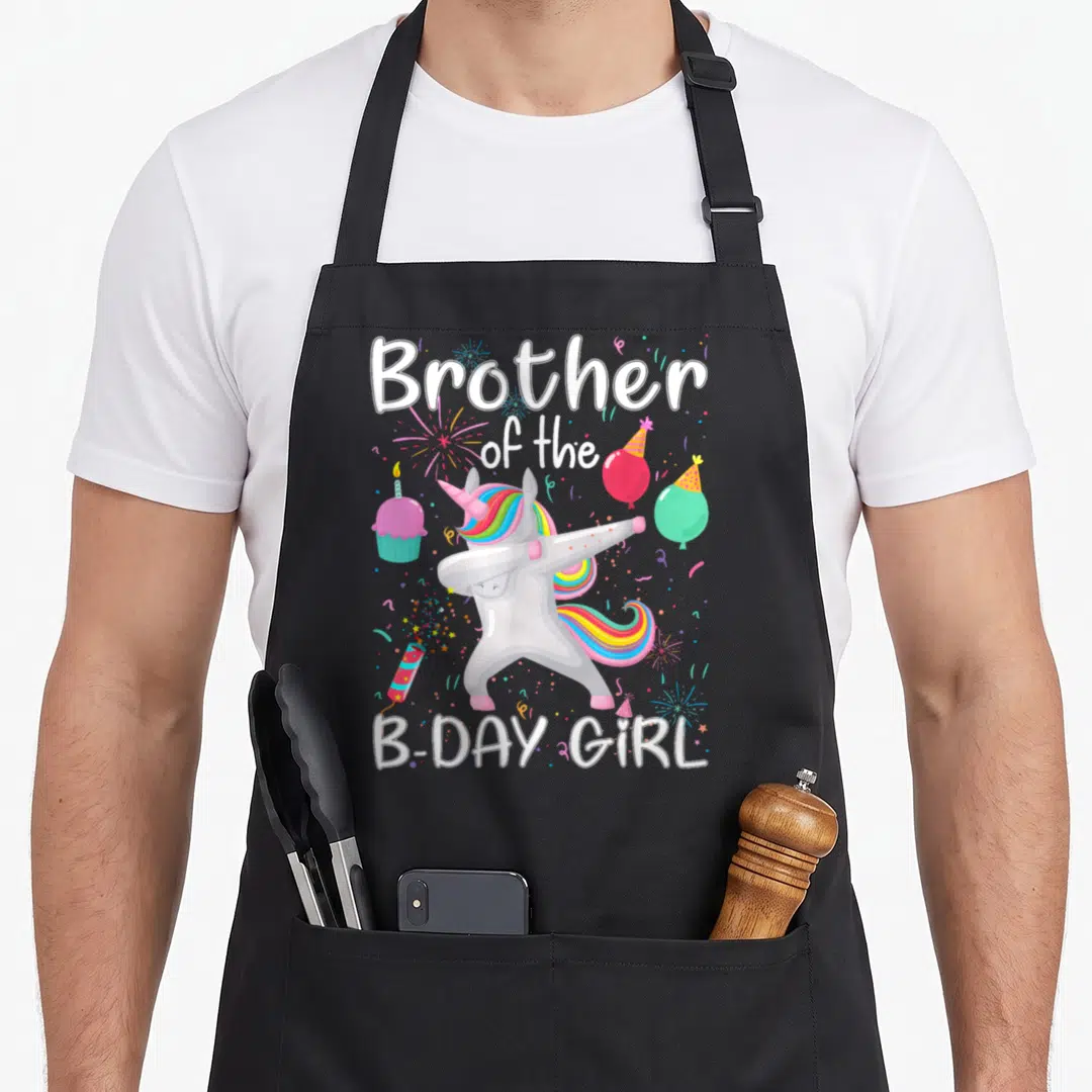 Swab birthday apron - Dabbing unicorn with rainbow mane and text Brother of the B-Day Girl surrounded by balloons — shown on a black cotton canvas apron against a white background