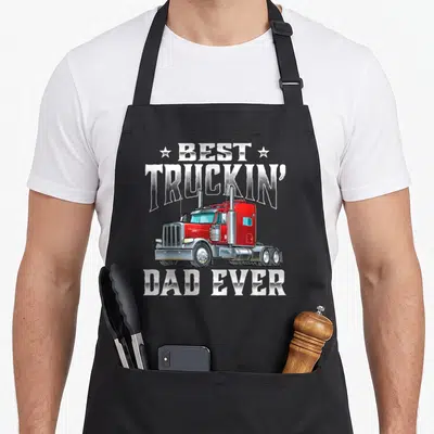 Truckin trucker semi truck apron - Red cartoon semi-truck with Best Truckin Dad Ever text and stars — shown on a black cotton canvas apron against a white background