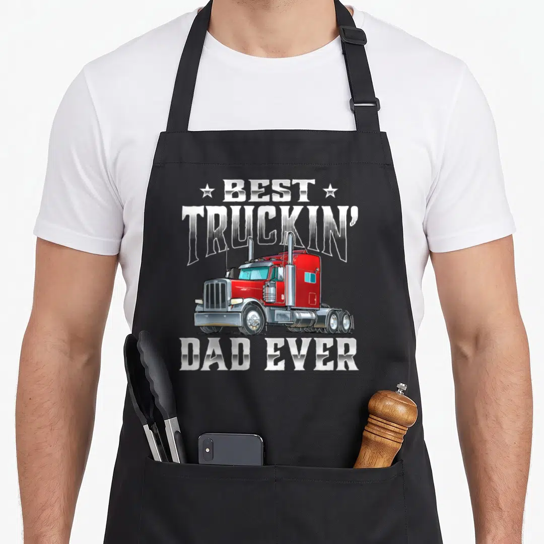Truckin trucker semi truck apron - Red cartoon semi-truck with Best Truckin Dad Ever text and stars — shown on a black cotton canvas apron against a white background
