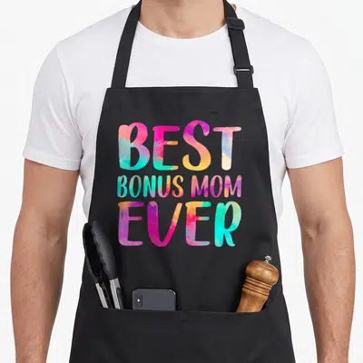Colorful mother's day aprons - Stacked BEST BONUS MOM EVER text in pink blue yellow and purple watercolor font — shown on a black cotton canvas apron against a white background