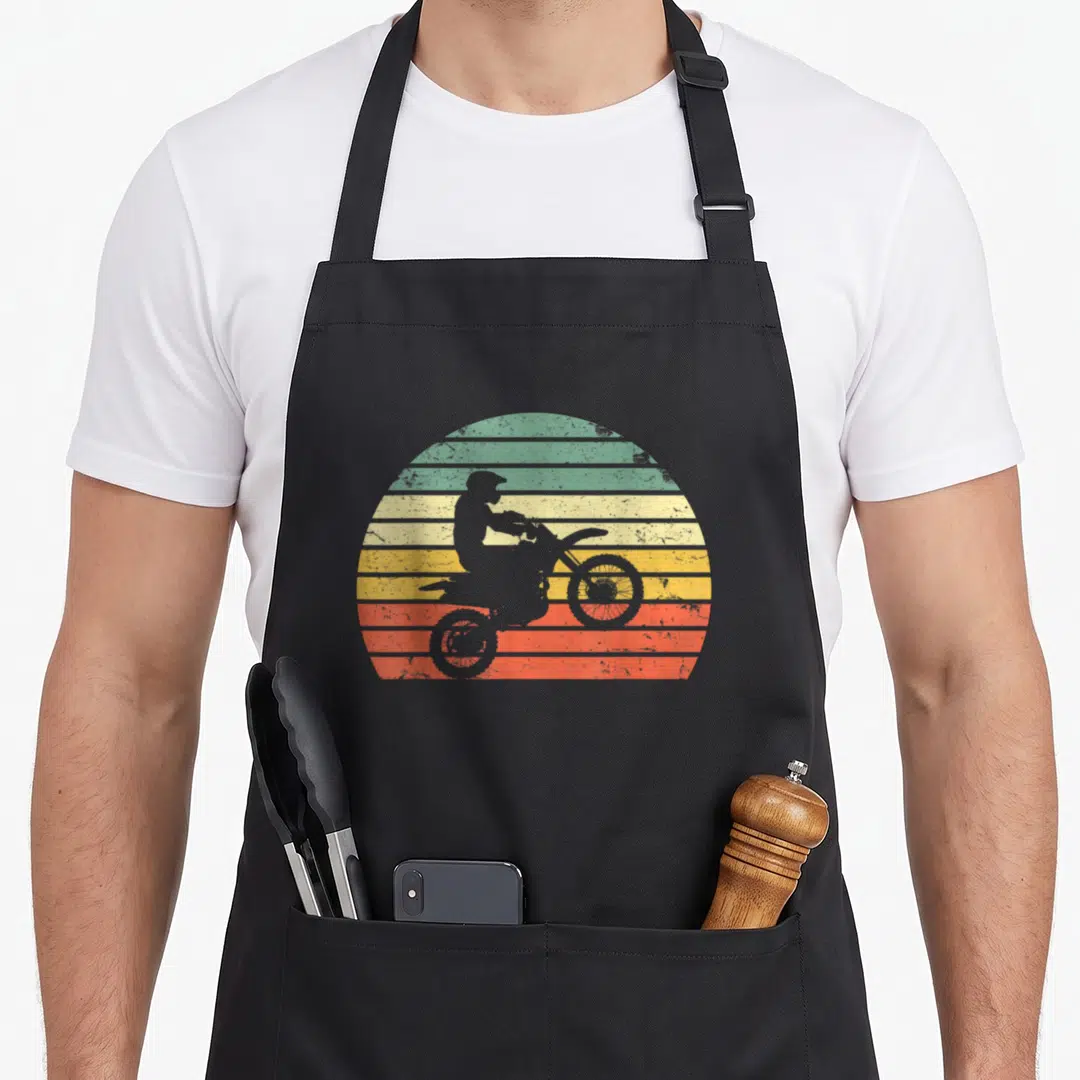 Dirt silhouette bike apron - Grey motocross rider silhouette on retro striped sun background — shown on a black cotton canvas apron against a white background