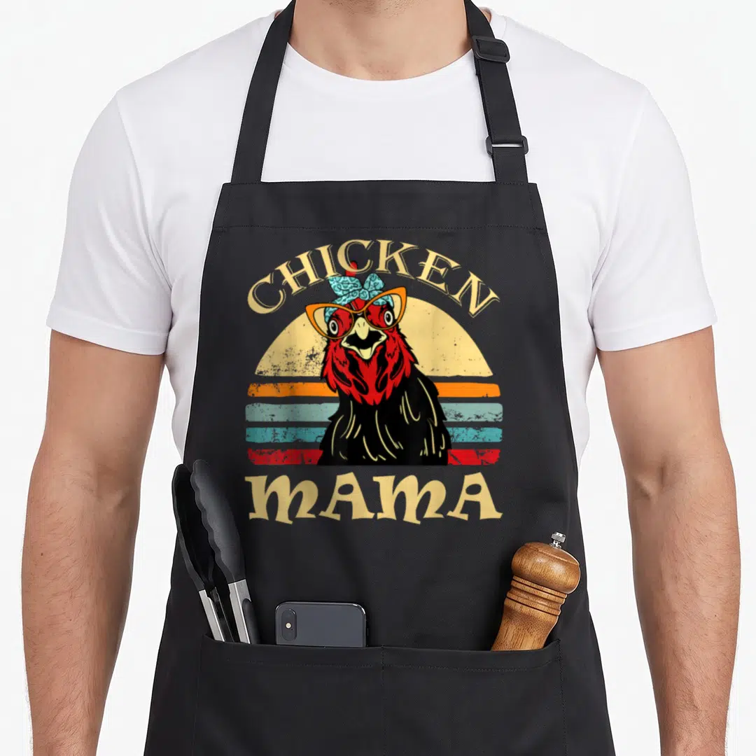Momma hen apron - Retro black chicken with glasses and bow under arched CHICKEN MAMA text — shown on a black cotton canvas apron against a white background
