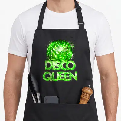 Disco queen themed 70s apron - Green disco ball with sparkles above stacked DISCO QUEEN text in tile pattern — shown on a black cotton canvas apron against a white background