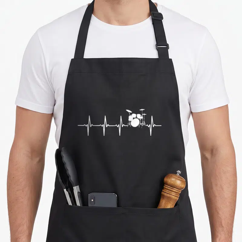 Heartbeat drum apron - White drum kit silhouette resting on a horizontal heartbeat pulse line — shown on a black cotton canvas apron against a white background