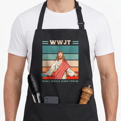 Would golf apron - Cartoon Jesus holding teal disc over striped background with WWJT text — shown on a black cotton canvas apron against a white background