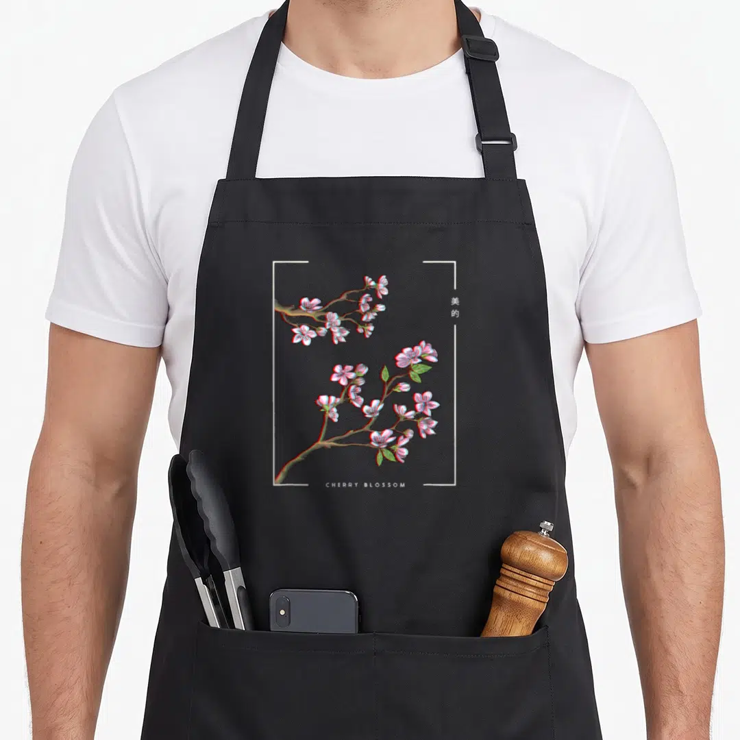 Japanese cherry print apron - Glitch style cherry blossom branch with pink flowers and CHERRY BLOSSOM text — shown on a black cotton canvas apron against a white background