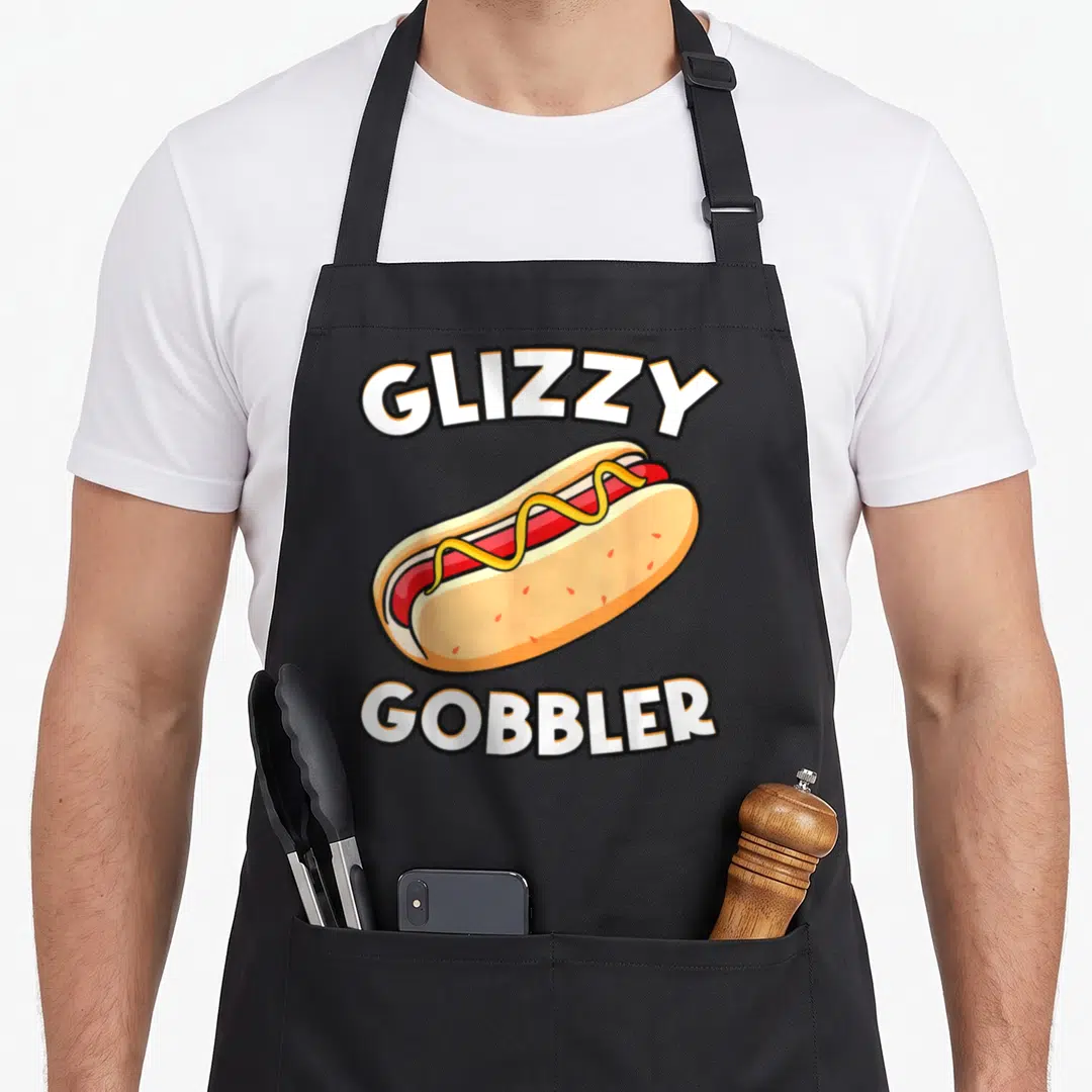 Glizzy hot dog apron - Cartoon hot dog with arched GLIZZY GOBBLER text in white and yellow — shown on a black cotton canvas apron against a white background