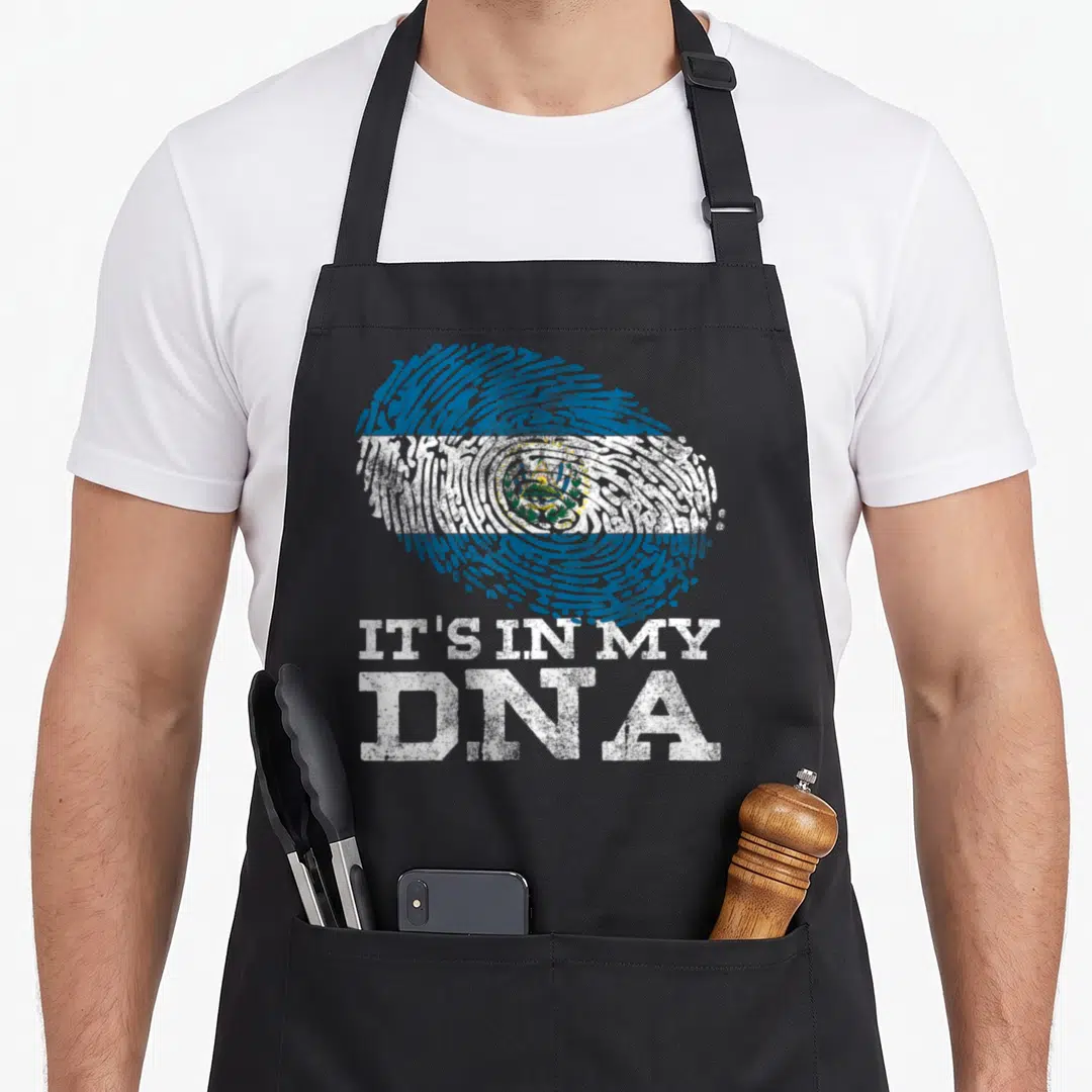 Dna salvadoran apron - Distressed fingerprint flag in blue white green with stacked white text IT'S IN MY DNA — shown on a black cotton canvas apron against a white background