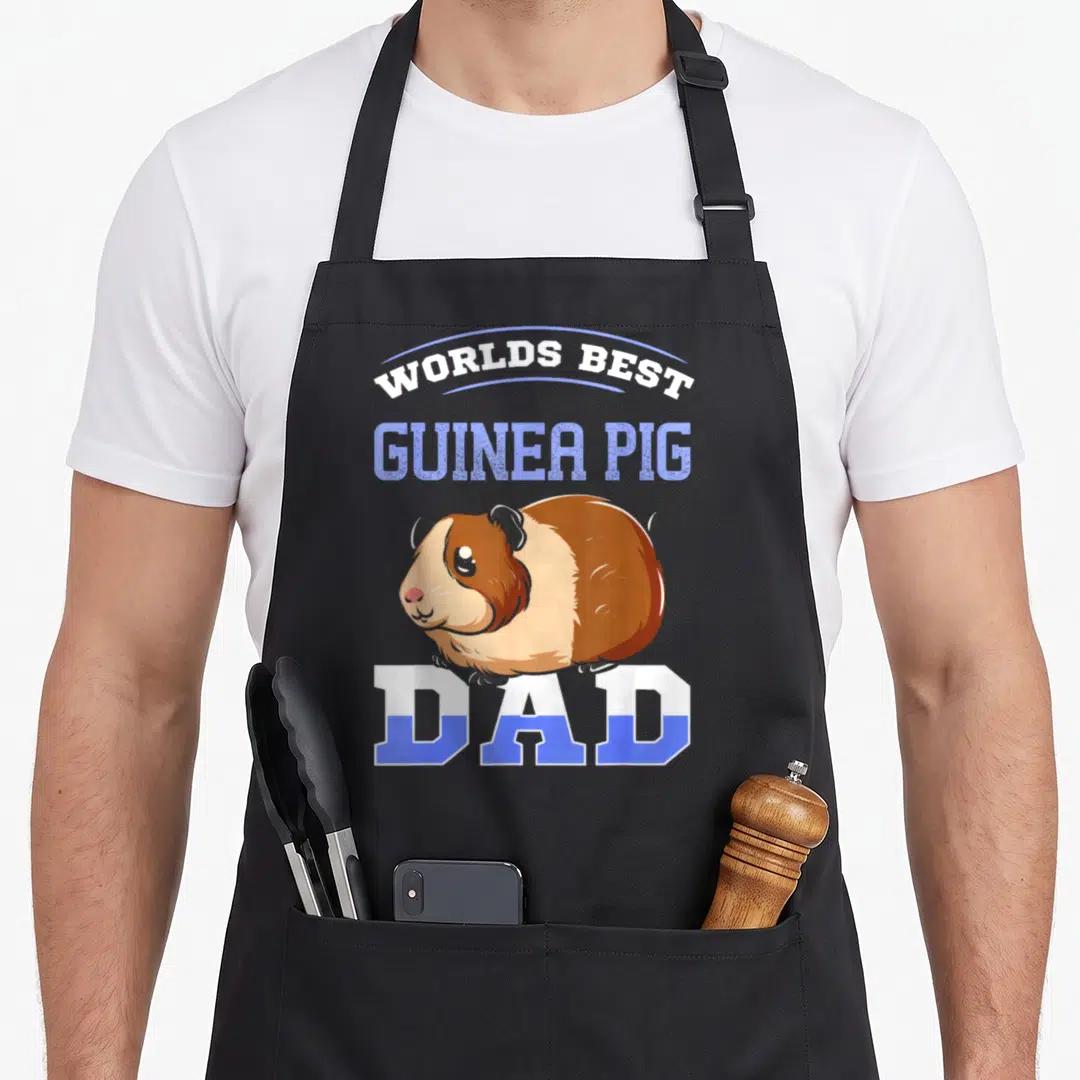 Cool pig guinea dad apron - Cartoon guinea pig with Worlds Best Guinea Pig Dad text in white and blue — shown on a black cotton canvas apron against a white background