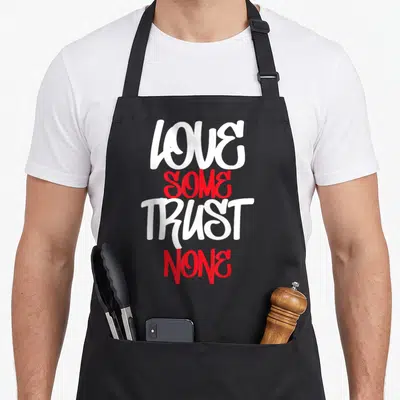 Hustler urban apron - Stacked LOVE SOME TRUST NONE text in white and red brush font — shown on a black cotton canvas apron against a white background