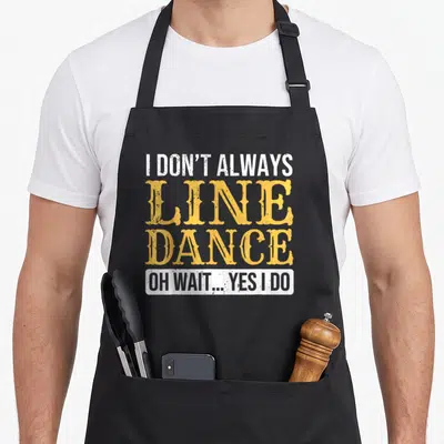 Dancer dance line apron - Stacked white and yellow text reading I DON'T ALWAYS LINE DANCE OH WAIT YES I DO inside — shown on a black cotton canvas apron against a white background