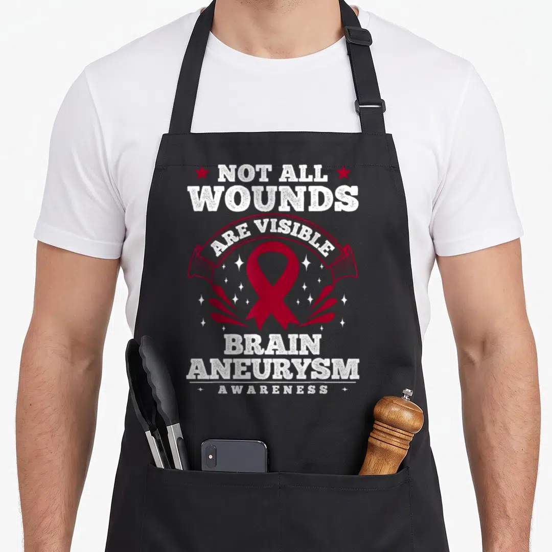 Wound aneurysm awareness apron - Red ribbon surrounded by white sparkles and stars with stacked text reading Not All — shown on a black cotton canvas apron against a white background