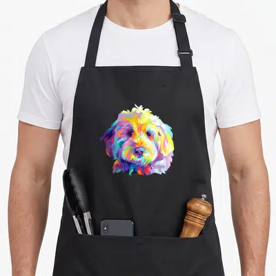 Colorful dog apron - Geometric dog head made of yellow, blue, pink, purple, and orange polygons centered on black fabric — shown on a black cotton canvas apron against a white background