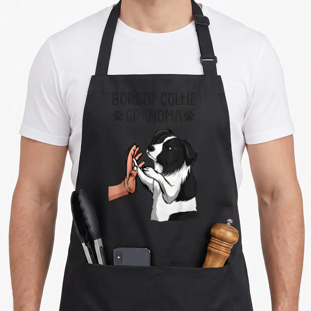 Grandma border collie apron - Cartoon border collie high-fiving a hand under stacked text with paw prints — shown on a black cotton canvas apron against a white background