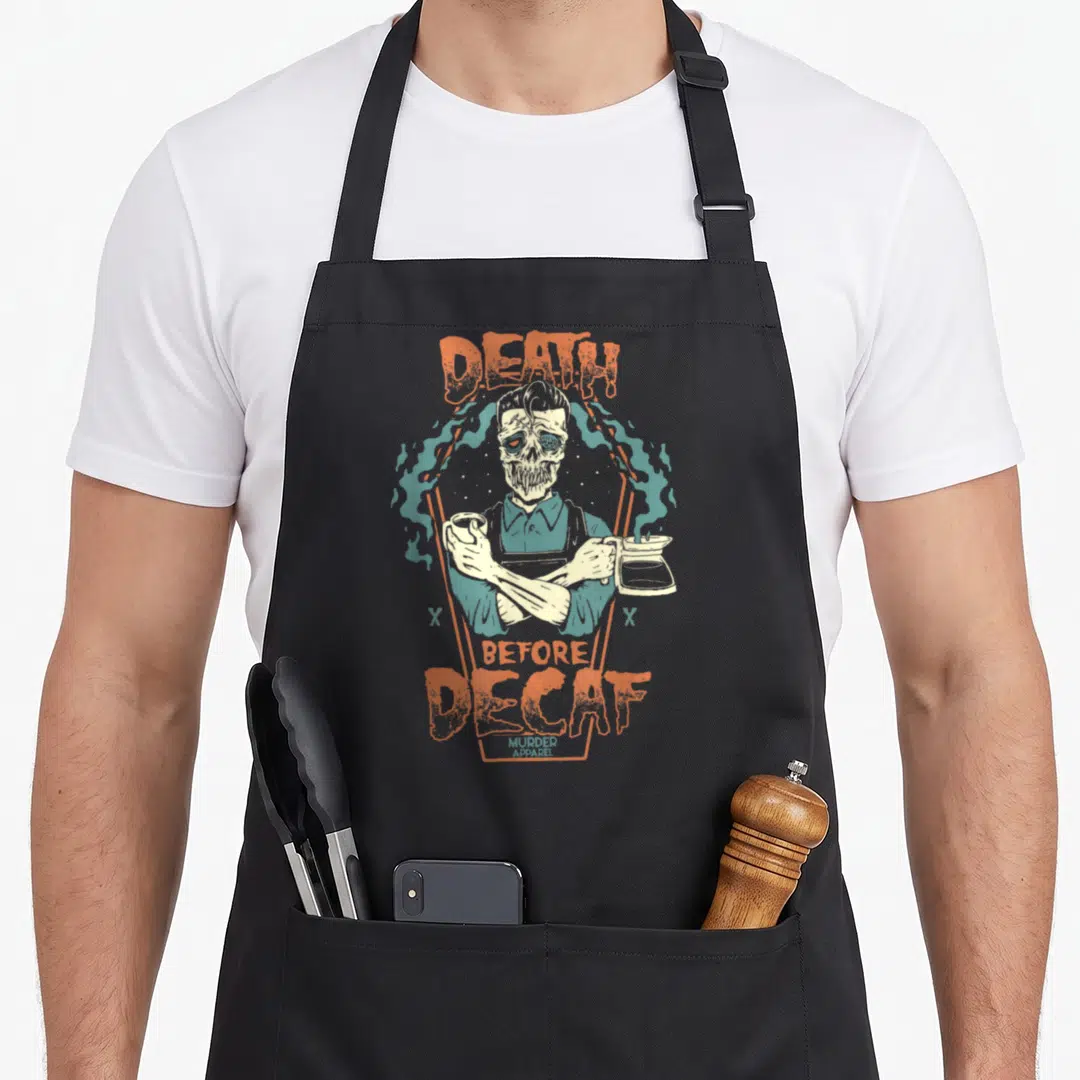 Addict coffee apron - Skeleton barista holding cup and pot with DEATH BEFORE DECAF text in orange and teal smoke — shown on a black cotton canvas apron against a white background