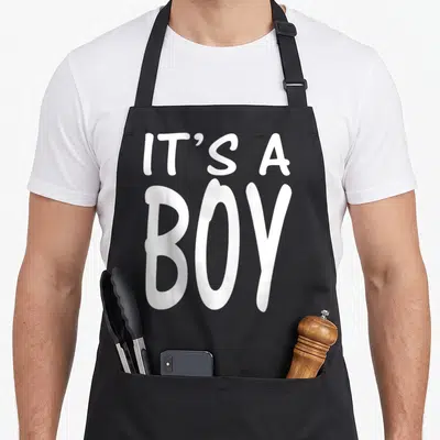 Blue baby shower apron - White IT'S A BOY stacked typography on black fabric — shown on a black cotton canvas apron against a white background