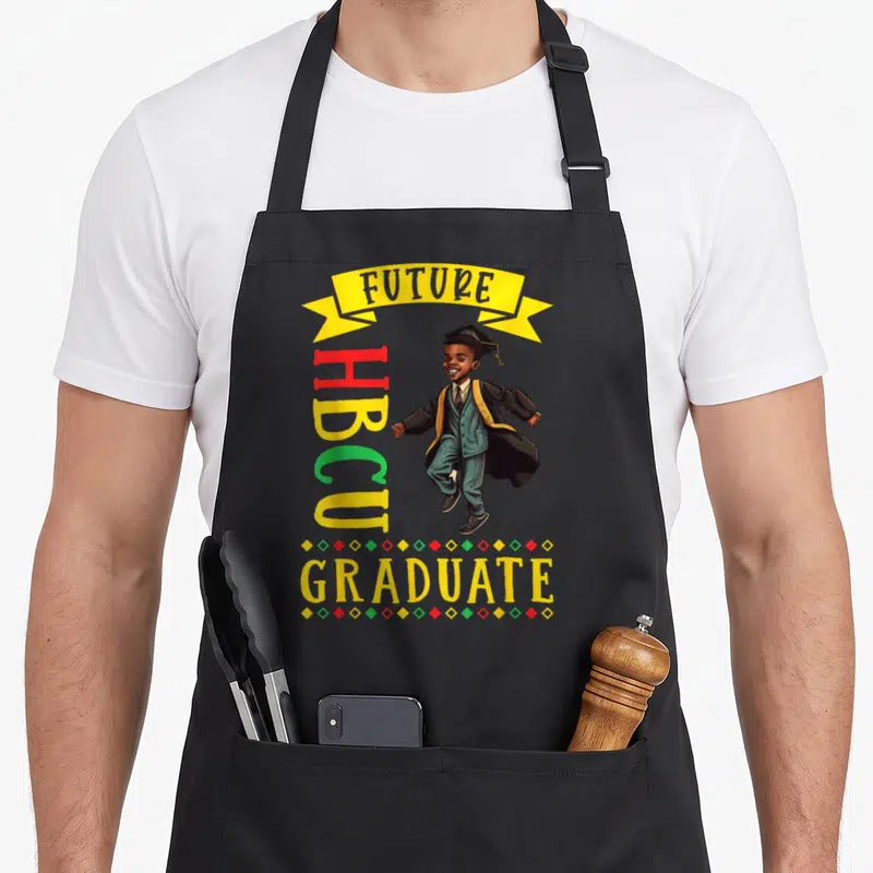 Future best college ever apron - Cartoon boy in graduation cap gown with FUTURE HBCU GRADUATE text and colorful diamonds — shown on a black cotton canvas apron against a white background