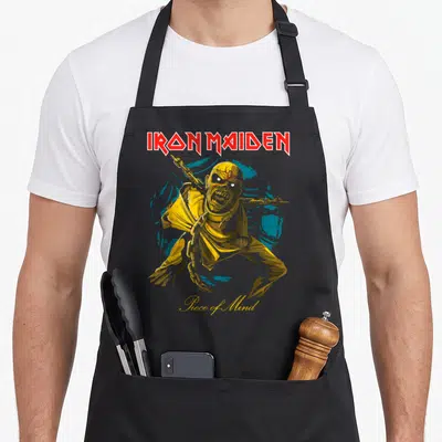 Pom camping apron - Cartoon mummy with chains in yellow and red in front of a blue circle under Iron Maiden text — shown on a black cotton canvas apron against a white background
