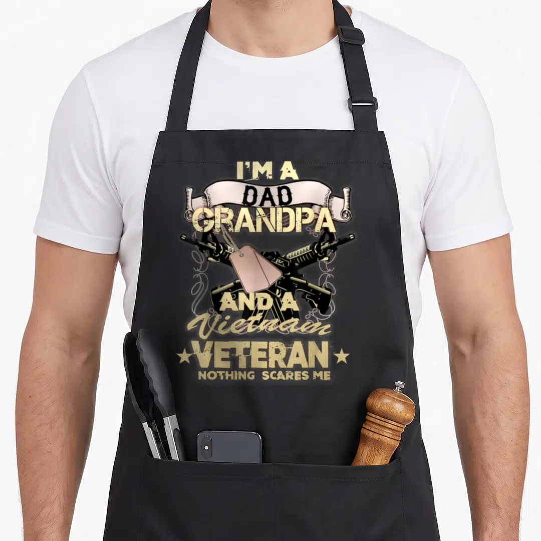 Vietnam retired soldier apron - Crossed rifles with pinkish-tan dog tags and stacked text reading I'm a Dad Grandpa — shown on a black cotton canvas apron against a white background