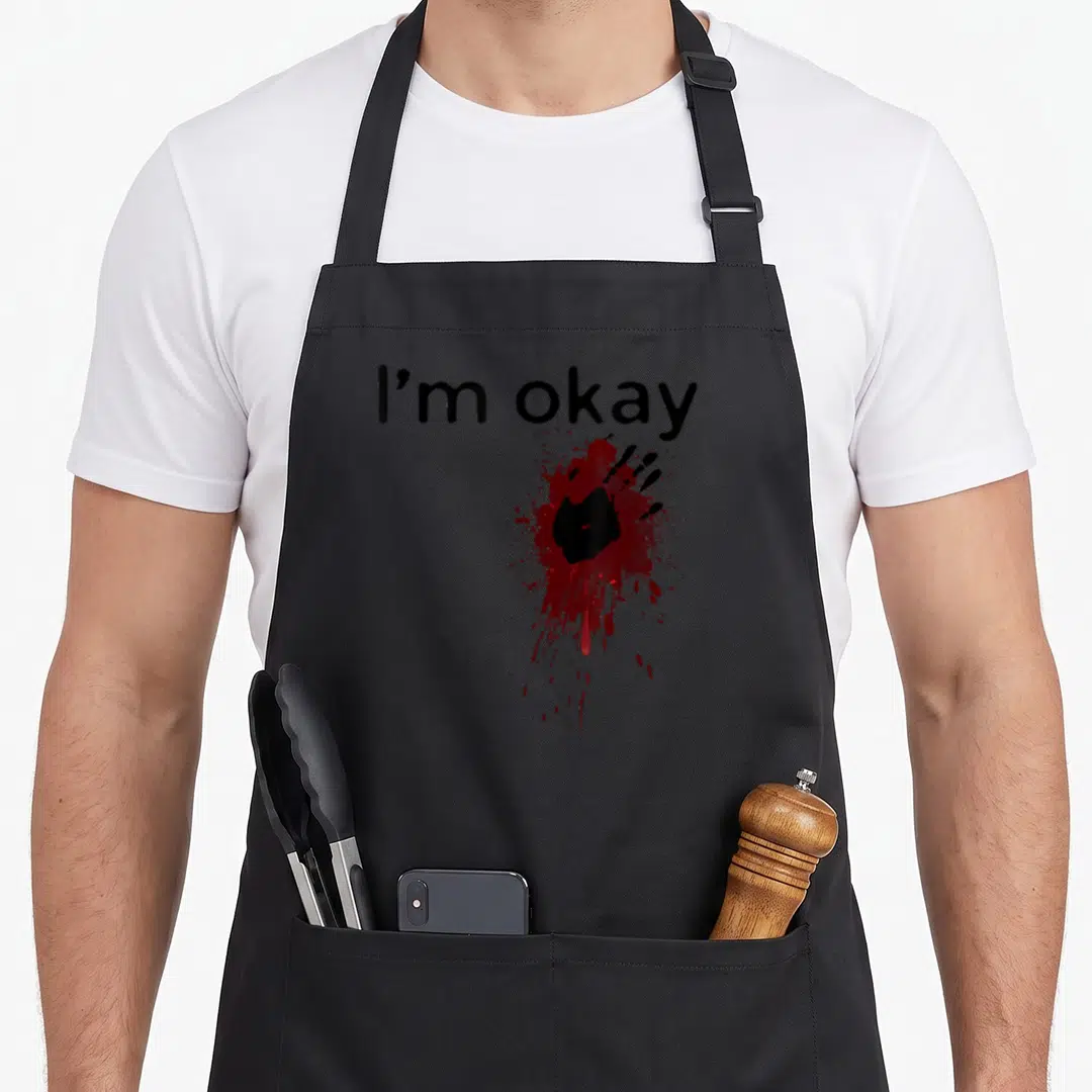 Okay halloween apron - I'm okay text above red blood splatter with black handprint silhouette — shown on a black cotton canvas apron against a white background