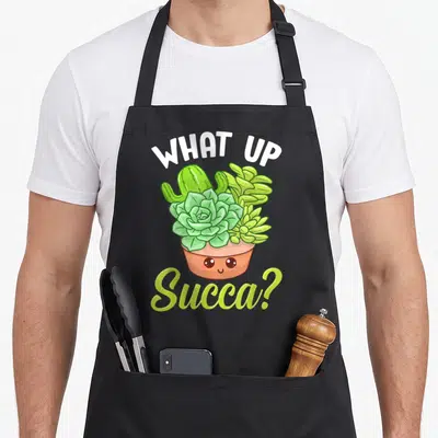 Punny cactus apron - Arched text surrounding a smiling terracotta pot filled with green succulents — shown on a black cotton canvas apron against a white background